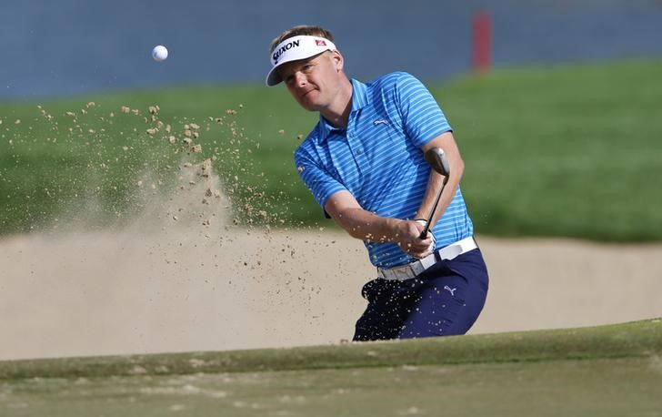 © Reuters. Denmark's Kjeldsen hits the ball out of the bunker on the first hole during the Abu Dhabi Golf championship