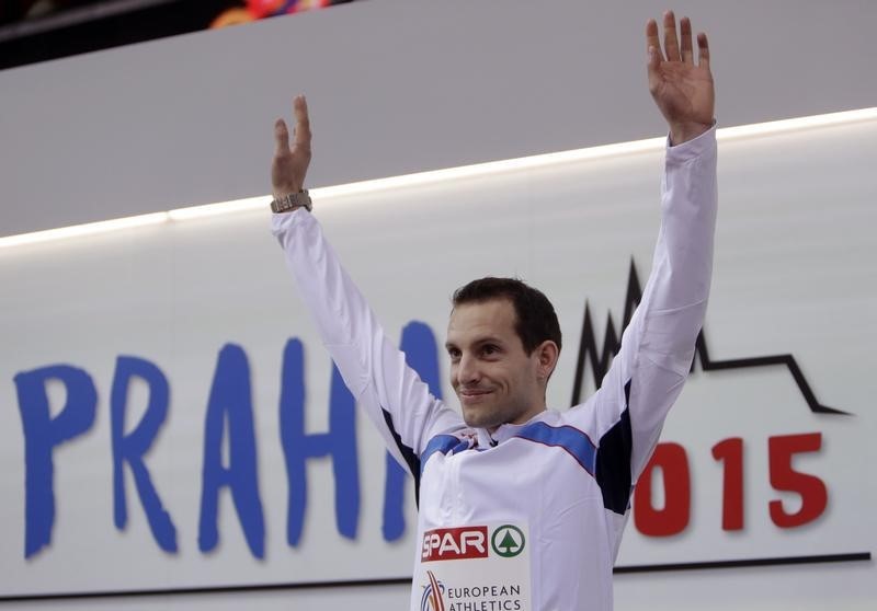 © Reuters. Winner Renaud Lavillenie celebrates on the podium at the medal ceremony for the men's pole vault final during the European Indoor Championships in Prague