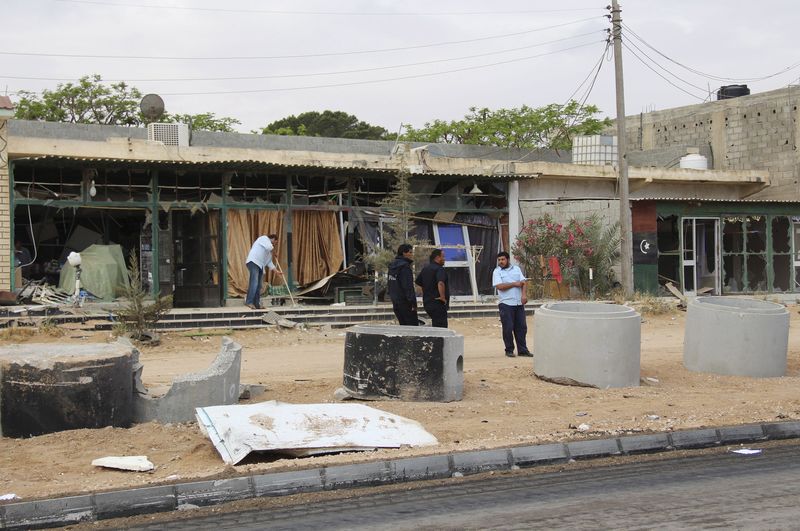 © Reuters. A man cleans his shop after a suicide car bomber blew himself up at a checkpoint in Dafniya 