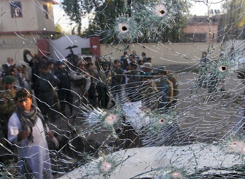 © Reuters. Afghan security forces are seen from a cracked side window of a vehicle, which was damaged in a suicide attack on a police headquarters in Jalalabad, Afghanistan 