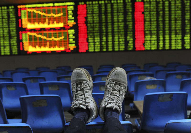 © Reuters. An investor puts his feet onto the back of a chairs in front of an electronic board displaying stock information at a brokerage house in Hefei