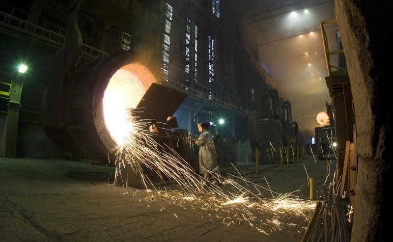 © Reuters. A worker cleans an industrial container for molten steel at the ArcelorMittal steel mill in Warsaw