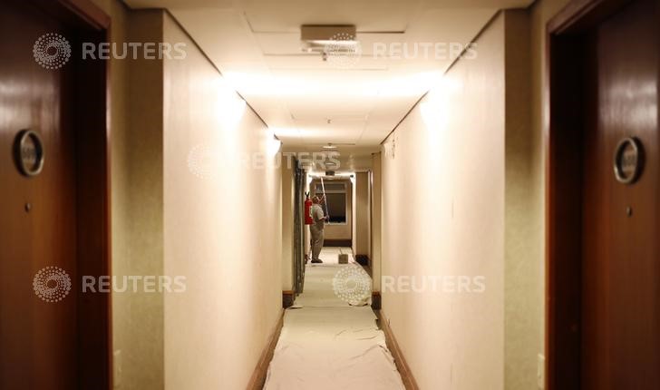 © Reuters. A worker paints the doorway of a hotel during the World Cup round of 16 match between Germany and Algeria in Sao Paulo