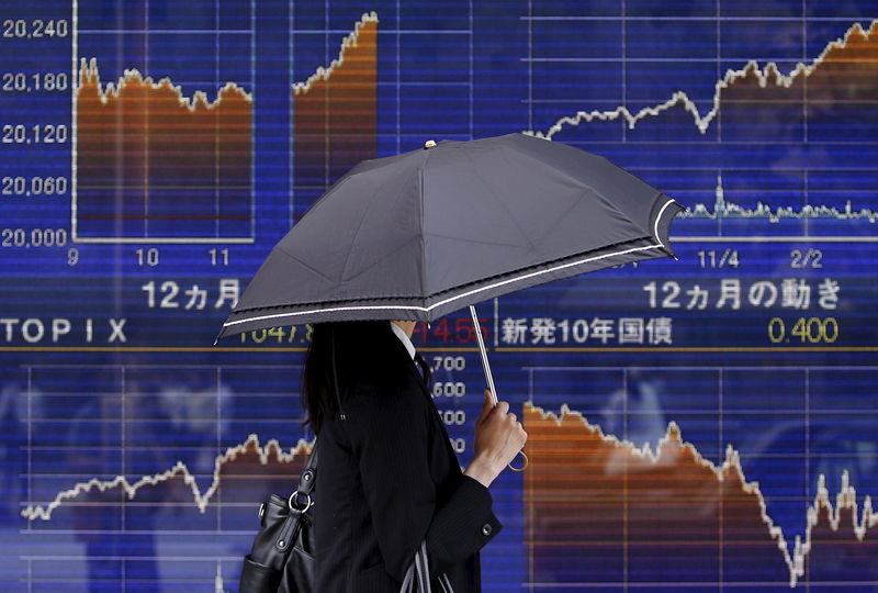 © Reuters. A pedestrian holding an umbrella walks past an electronic board showing the graph of the recent fluctuations of Japan's Nikkei average outside a brokerage in Tokyo