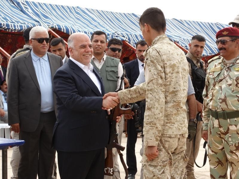 © Reuters. Prime Minister Haidar al-Abadi shakes hands with a Sunni tribesman at Camp Habbaniyah, in the eastern city of Ramadi 