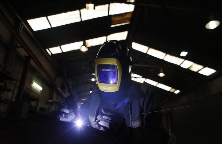 © Reuters. Mitsos Dan, a worker from Albania, welds parts of agricultural machinery at a factory in Athens