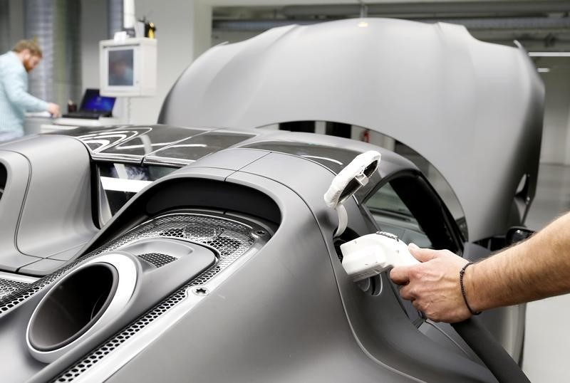 © Reuters. A worker charges a new Porsche 918 Spyder e-hybrid sports car at the Porsche factory in Stuttgart-Zuffenhausen