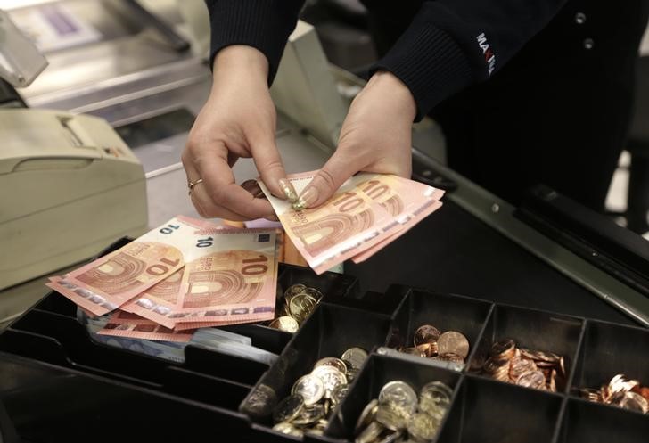 © Reuters. A cashier counts euro banknotes before a shop opens in Vilnius