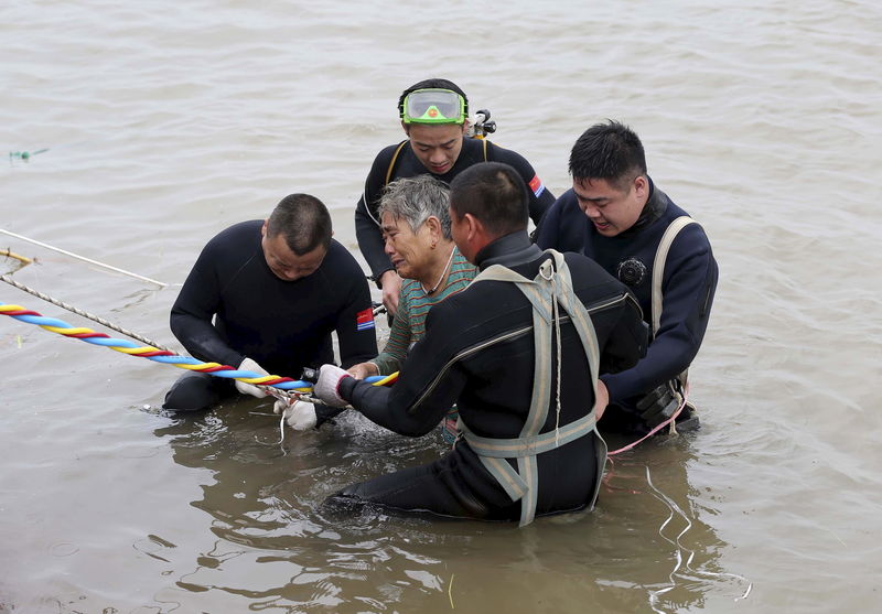 © Reuters. Mergulhadores ajudam vítima após resgatá-la de naufrágio no rio Yangtze, China