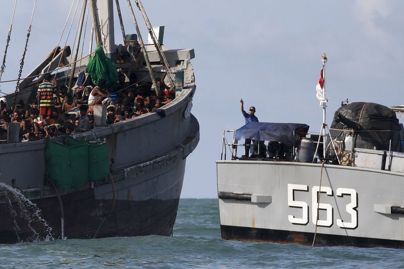 © Reuters. Oficial de barco militar de Mianmar fala com imigrantes em barco no mar de Andaman