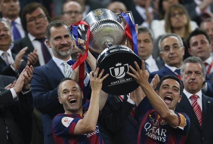 © Reuters. Xavi e Iniesta levantam a taça da Copa do Rei conquistada pelo Barcelona no sábado