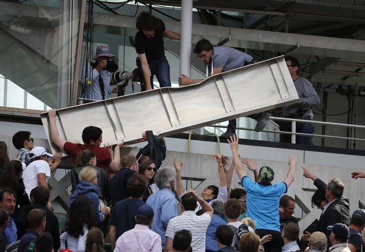 © Reuters. Espectadores removem estrutura de metal que caiu do placar da quadra Philippe Chartier, durante partida do Aberto da França, no complexo de Roland Garros, em Paris