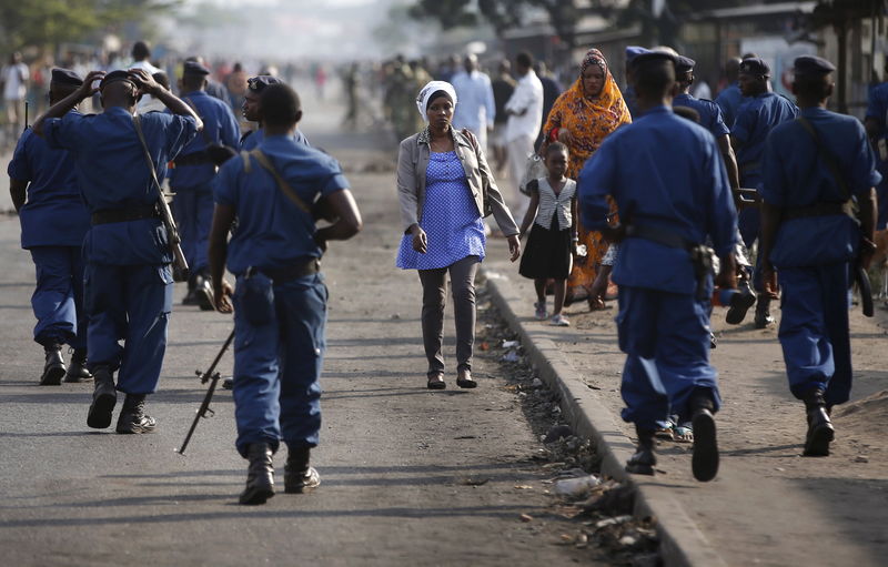 © Reuters. Woman passes by policemen during a protest against Burundi President Pierre Nkurunziza and his bid for a third term in Bujumbura