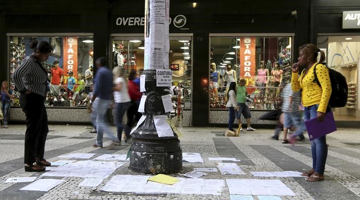 © Reuters. Pessoas olhando ofertas de emprego coladas em um poste no centro de São Paulo