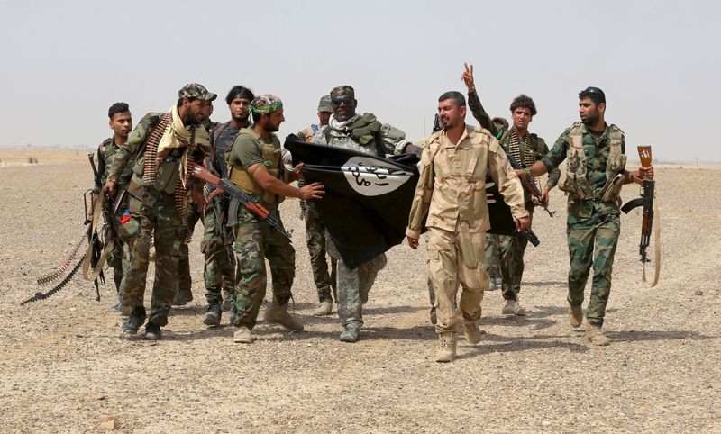 © Reuters. Paramilitares xiitas iraquianos e soldados iraquianos seguram bandeira do Estado Islâmico que dizem ter pego em Nibai, na província de Anbar