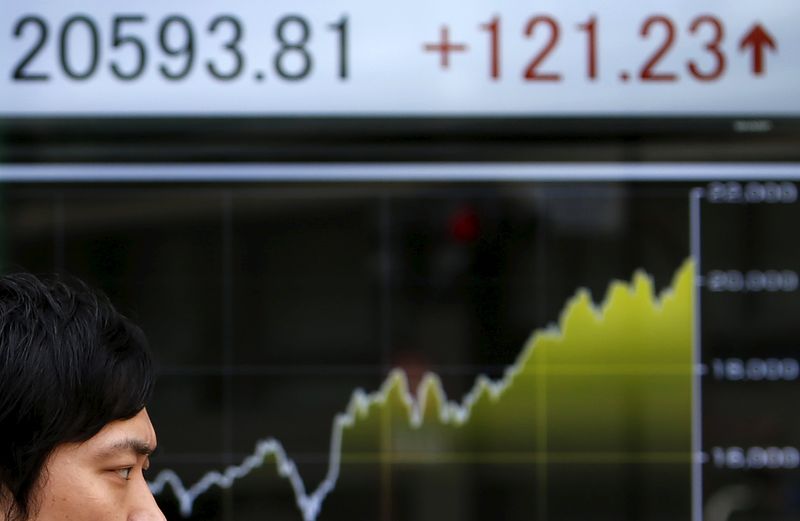 © Reuters. A pedestrian walks past an electronic board showing the graph of the recent fluctuations of the Japan's Nikkei average outside a brokerage in Tokyo