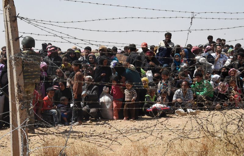 © Reuters. Syrian refugees wait behind the border fence to cross into Turkey on the Turkish-Syrian border, near the southeastern town of Akcakale in Sanliurfa province, Turkey