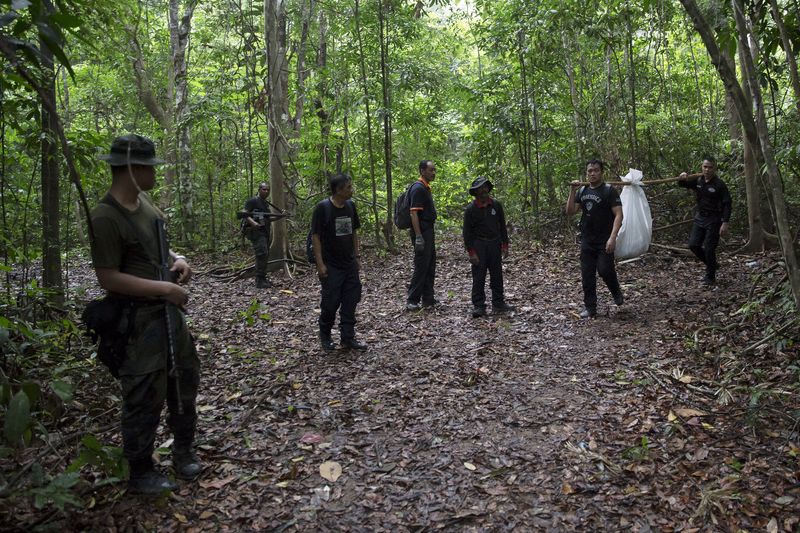 © Reuters. Members of a police forensic team carry a body bag with human remains dug from the grave near the abandoned human trafficking camp in the jungle close the Thailand border at Bukit Wang Burma in northern Malaysia