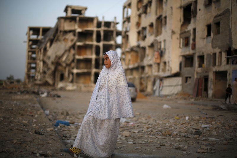 © Reuters. Palestinian girl stands near residential buildings that witnesses said were heavily damaged by Israeli shelling during a 50-day war last summer, in Beit Lahiya town in the northern Gaza Strip 