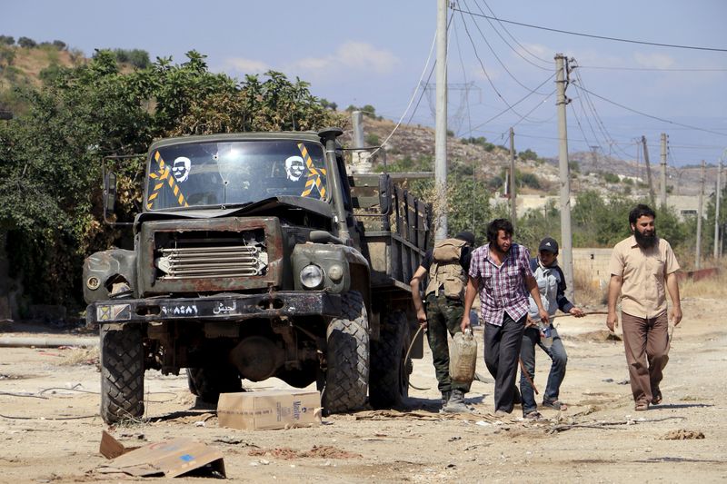 © Reuters. Fighters from a coalition of rebel groups called "Army of Fatah" walk beside a military truck that used to belong to the forces of Syria's President Assad near Psoncol town, in the Idlib countryside, Syria