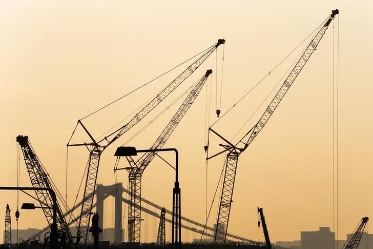 © Reuters. Cranes are pictured against sunset at a construction site in Tokyo