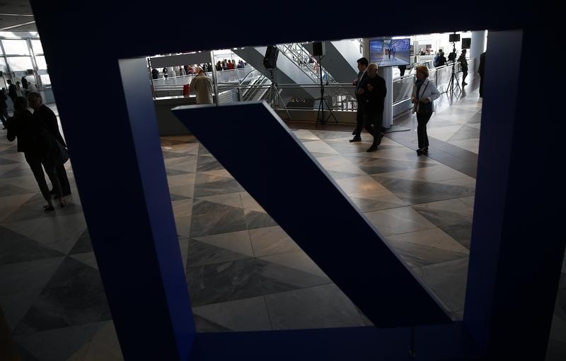 © Reuters. People walk past a Deutsche Bank logo ahead the banks annual general meeting in Frankfurt