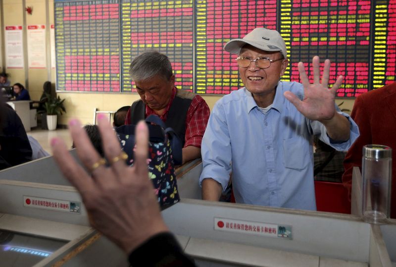 © Reuters. A man gestures "five" to another investor as the Shanghai Composite Index reached 5,000 points, in front of an electronic board showing stock information at a brokerage house in Nantong