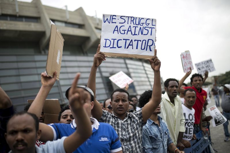 © Reuters. Eritrean refugees hold placards during a protest against the Eritrean government outside their embassy in Tel Aviv, Israel 