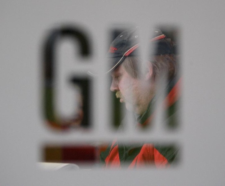 © Reuters. A worker walks behind a logo of General Motors after the announcement of the closing of the Opel assembly plant in Antwerp