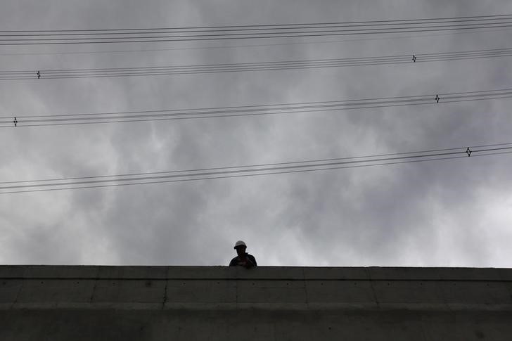 © Reuters. Worker stands below power lines at a underpass affected by heavy rains in Monterrey