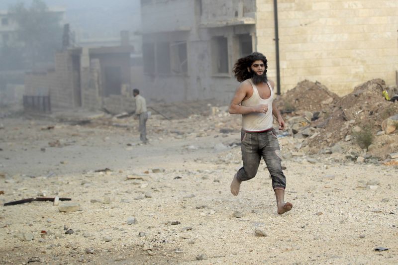 © Reuters. A man runs in at a site damaged by what activists said was a barrel bomb dropped by forces loyal to Syria's president Bashar Al-Assad in Maarat Al-Nouman, south of Idlib