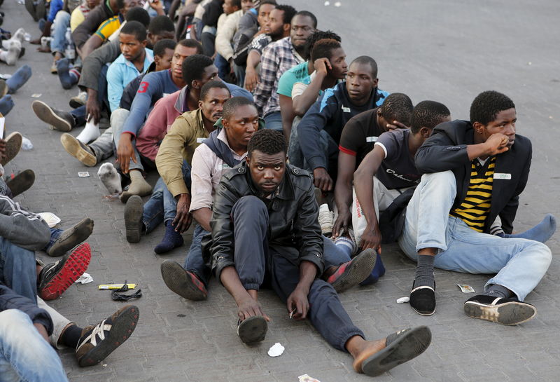 © Reuters. Migrants rest after disembarking from the British assault ship HMS Bulwark at the Sicilian port of Catania after being rescued at sea