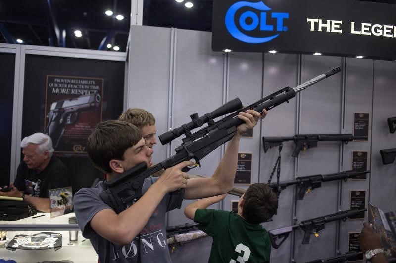 © Reuters. A teenager takes aim with a gun made by Colt at an exhibit booth during the National Rifle Association's annual meeting in Houston