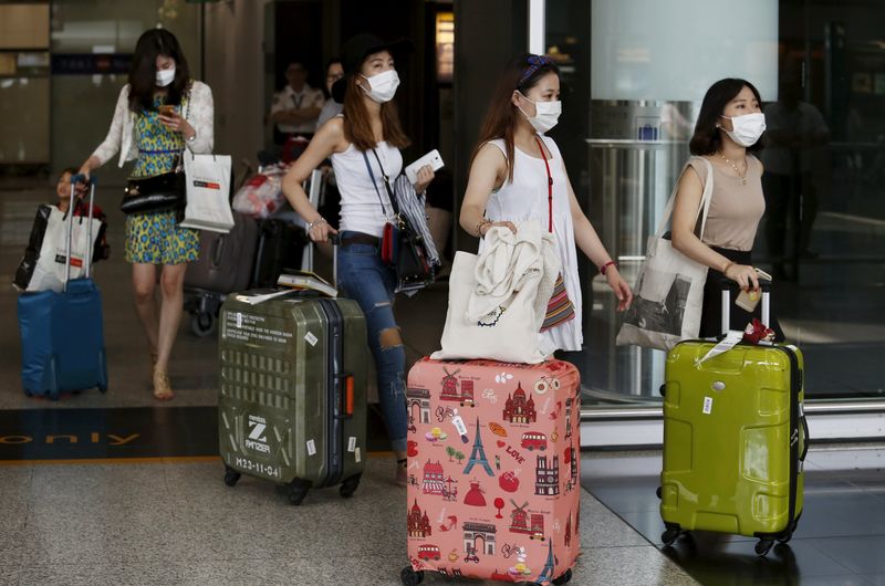 © Reuters. South Korean visitors arriving from Seoul are seen wearing masks at Hong Kong Airport in Hong Kong