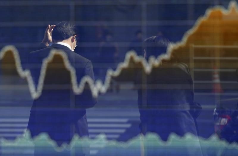 © Reuters. Man is reflected on an electronic board displaying a graph of Japan's Nikkei share average outside a brokerage in Tokyo