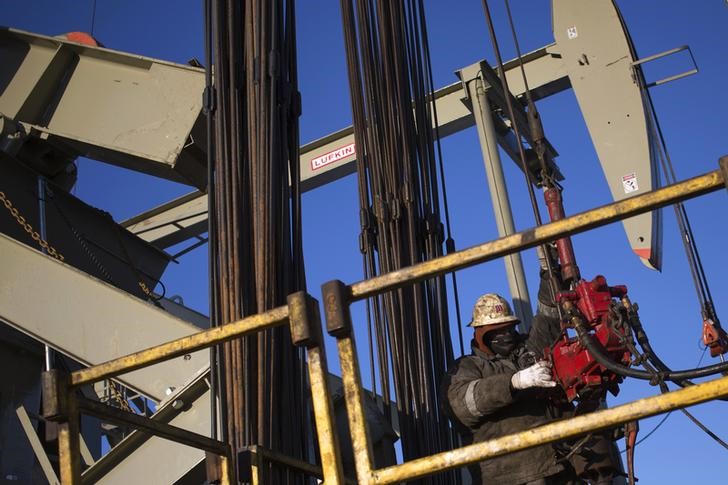 © Reuters. A man works on the rig of an oil drilling pump site in McKenzie County outside of Williston