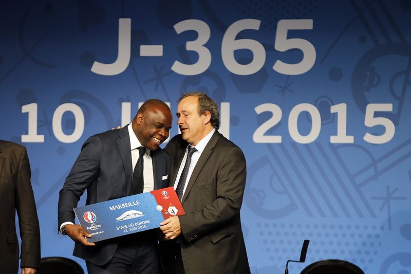 © Reuters. UEFA President Michel Platini presents a facsimile of an Euro 2016 ticket to former soccer player Basile Boli during a news conference a year before the start of Euro 2016, in Paris