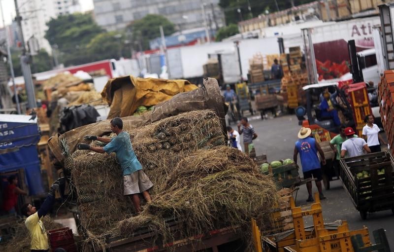 © Reuters. Funcionários descarregam abacaxis e transportam alimentos na Ceagesp