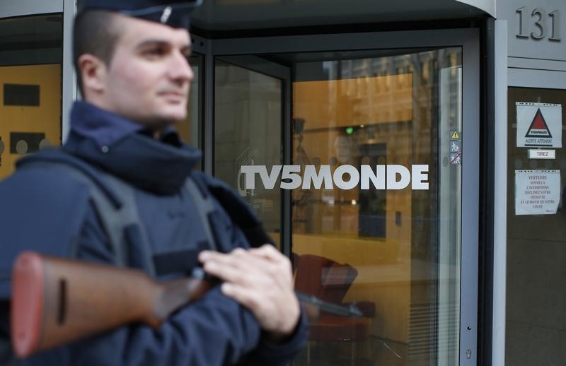 © Reuters. A French police officer stands guard in front of the main entrance of French television network TV5Monde headquarters