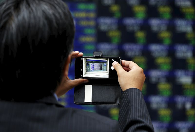 © Reuters. A man takes a photo of an electronic stock quotation board with his smartphone outside a brokerage in Tokyo