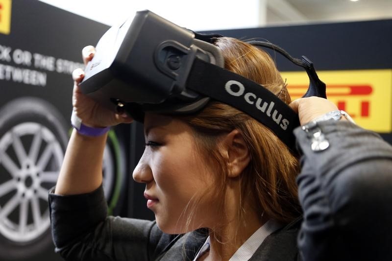 © Reuters. A woman puts on an Oculus virtual reality headset  during preparations for the 2014 LA Auto Show in Los Angeles