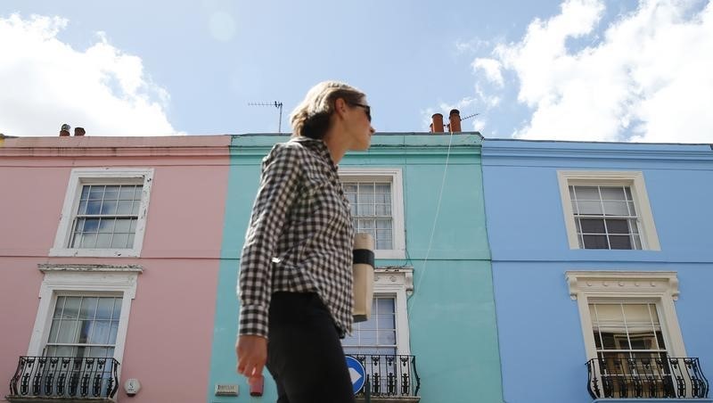 © Reuters. A woman walks past a row of houses in London