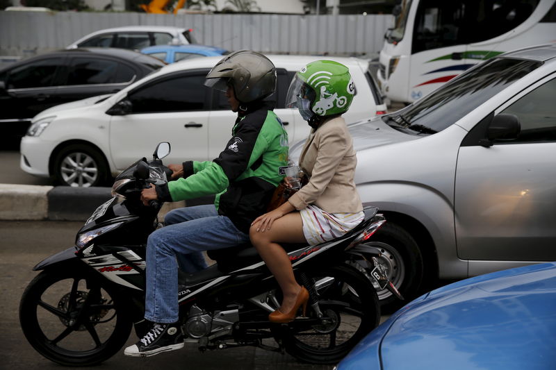 © Reuters. A Gojek driver pillions a customer as he rides his motorcycle through a business district street in Jakarta