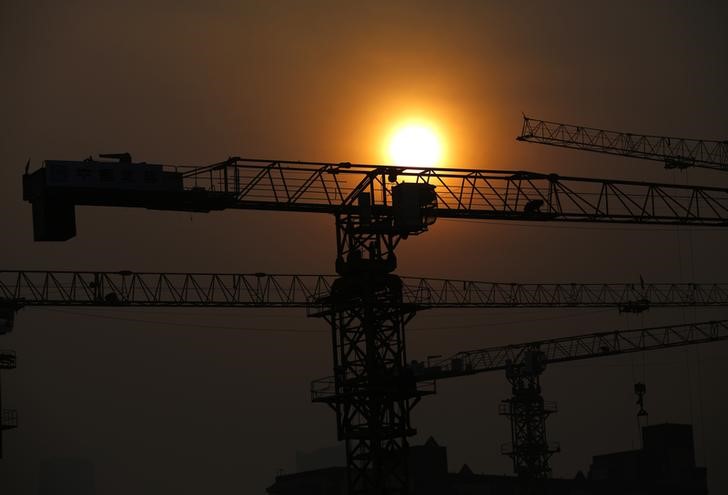 © Reuters. Cranes are silhouetted in front of the setting sun at a construction site for a new residential and commercial complex in Beijing