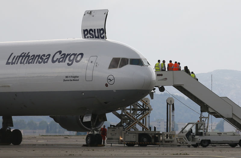 © Reuters. Workers stand on the staircase lifted to a Lufthansa cargo plane after it landed on the tarmac at the Marseille Provence Airport in Marignane as Lufthansa prepares to transport coffins with the remains of 44 victims of the Germanwings Airbus A320 crash