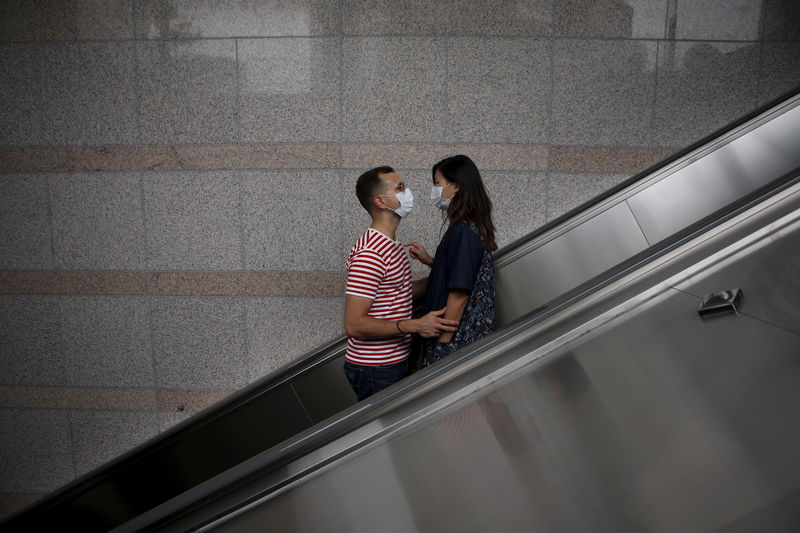 © Reuters. A couple wearing masks to prevent contracting Middle East Respiratory Syndrome (MERS) looks at each other as they ride on an escalator in Seoul