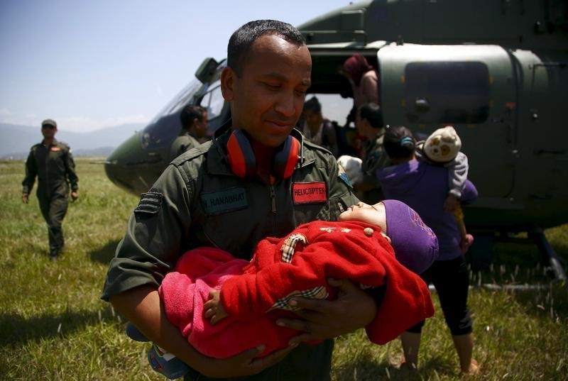© Reuters. A Nepalese army personnel holds the baby of an earthquake victim after being airlifted from Sindhupalchok District to Kathmandu