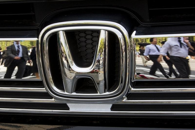 © Reuters. People are reflected in chrome front grill of Honda car outside Japanese car maker's headquarters in Tokyo