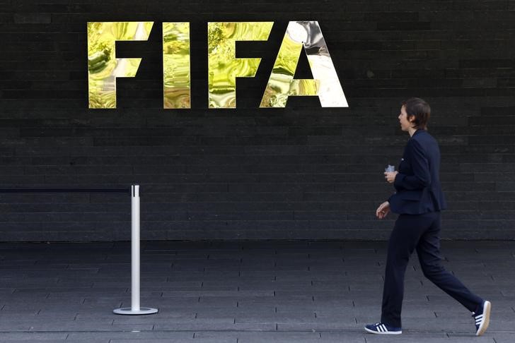 © Reuters. A staff walks past a logo of soccer's international governing body FIFA at their headquarters in Zurich