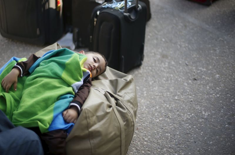 © Reuters. Palestinian boy sleeps as he waits with his family for a travel permit to cross into Egypt, at the Rafah border crossing between Egypt and the southern Gaza Strip